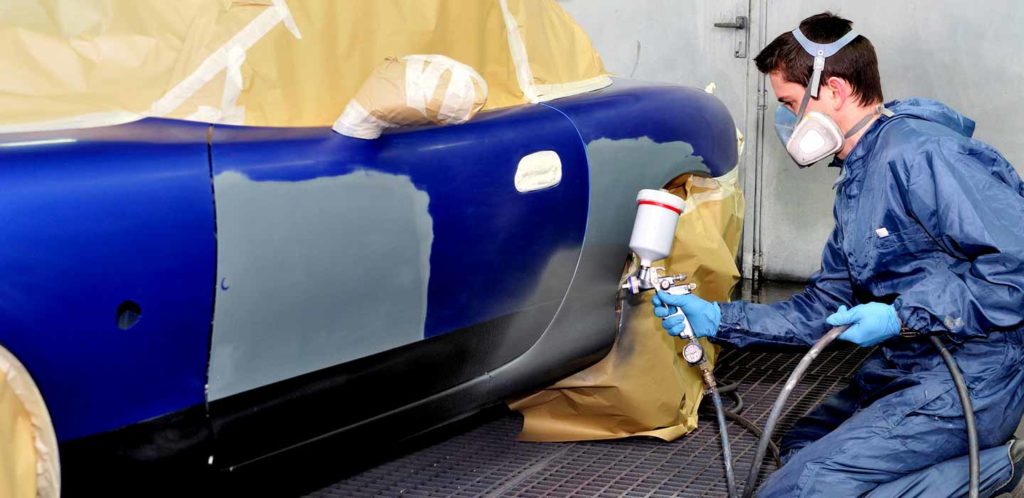 Man spray painting an auto collision repair